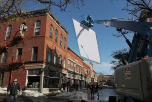 A giant diffusion screen is hoisted from a cherry picker Wednesday during filming of the HBO miniseries "Olive Kitteridge" on Main Street in downtown Gloucester. (Mike Springer)